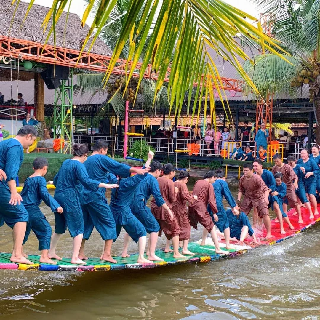 Hai đội áo xanh và áo nâu níu vai nhau giữ thăng bằng trên cầu nhún nhiều màu sát mặt nước